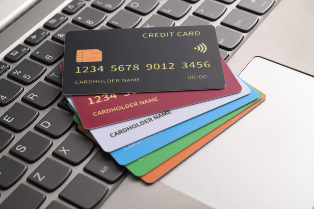 Vários cartões de crédito coloridos empilhados sobre um teclado de computador, representando segurança financeira e compras online.