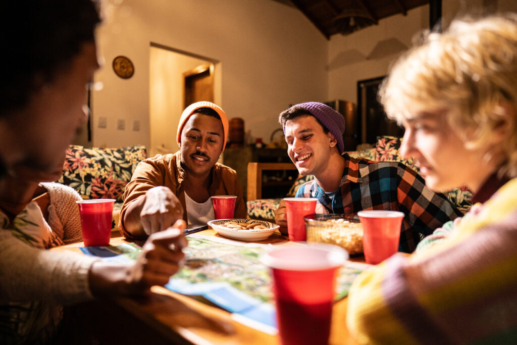 Grupo de amigos sorridentes compartilhando uma refeição em casa, criando momentos de conexão e alegria ao redor da mesa.